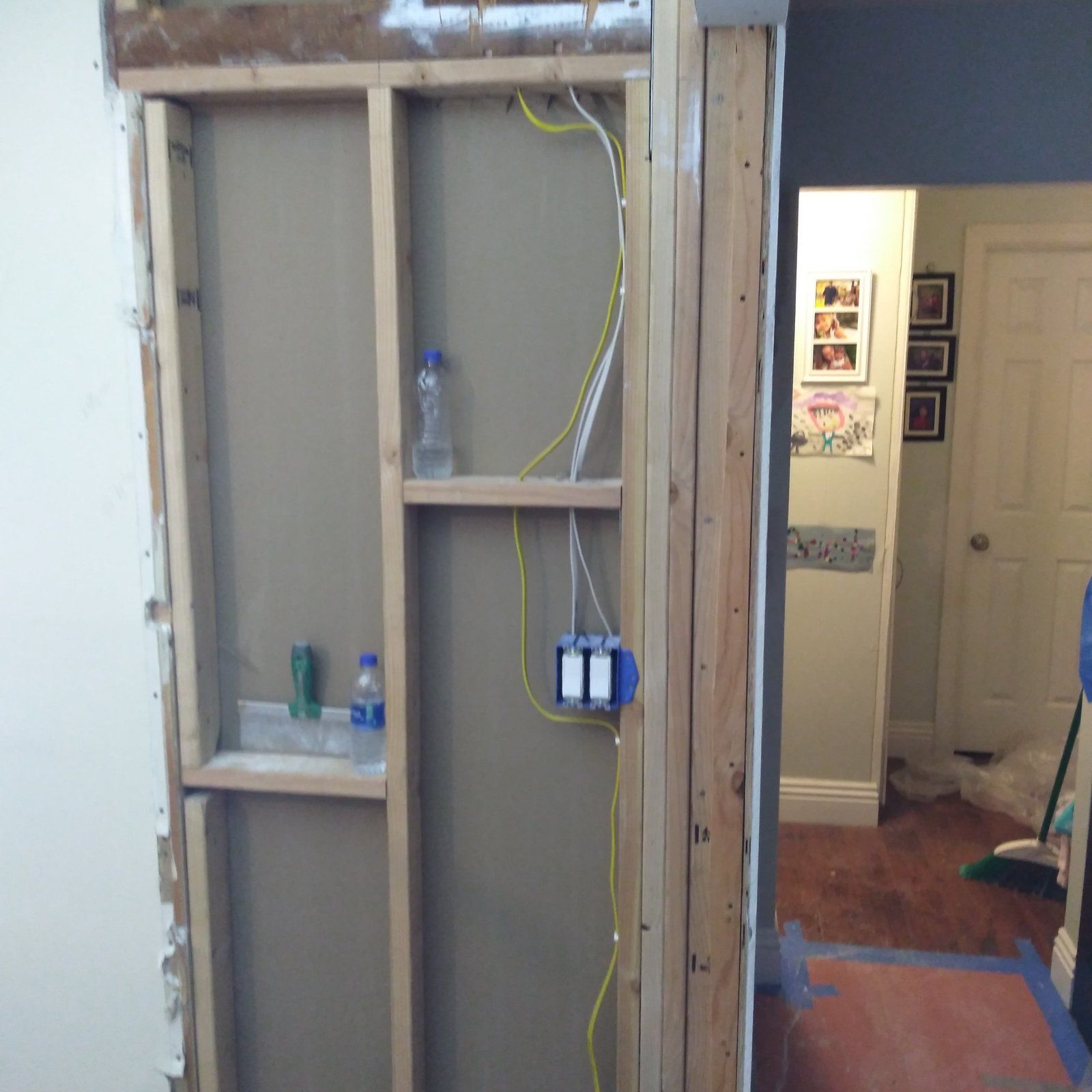 Wood framing with wiring run and blue painter's tape on the trim
